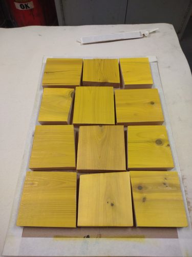 a 3x4 grid of cedar rectangles set into a grid, coated in yellow ink.